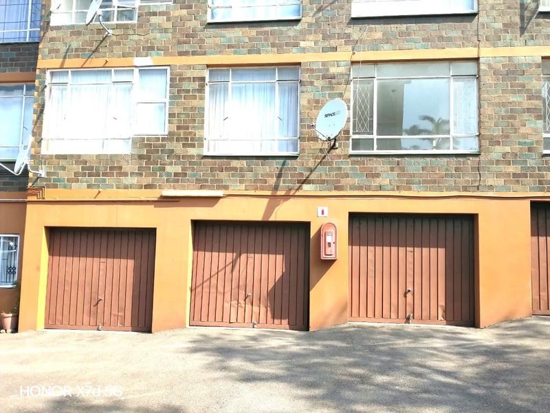 Exterior view of an apartment building featuring multiple garage doors, brick facade, and visible fire safety equipment.