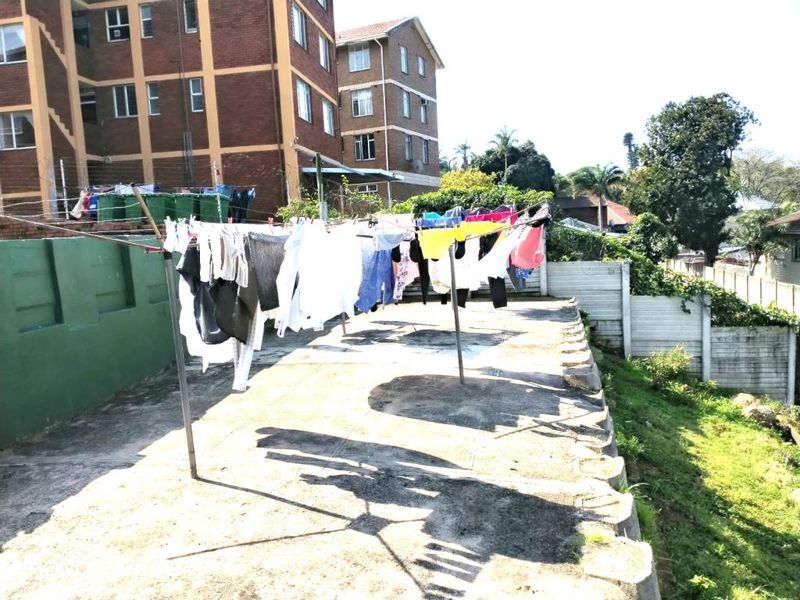 Rear exterior area featuring a concrete surface, boundary wall, and communal washing line facilities.