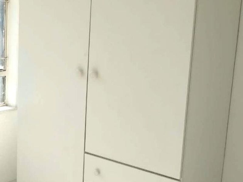 A bedroom featuring a white built-in wardrobe with integrated drawers and tiled flooring.