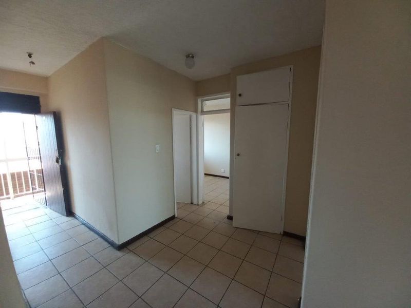 A functional hallway featuring tiled flooring and a built-in storage cupboard, providing access to adjacent rooms within the apartment.