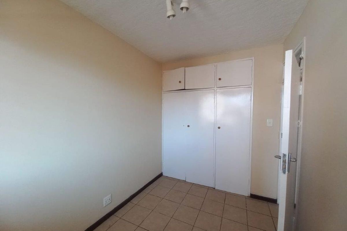An empty bedroom featuring built-in cupboards and tiled flooring, offering a blank canvas for personalization and interior design updates.