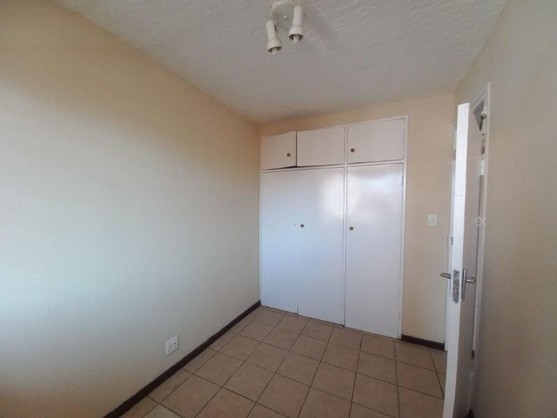 An empty bedroom featuring built-in cupboards and tiled flooring, offering a blank canvas for personalization and interior design updates.