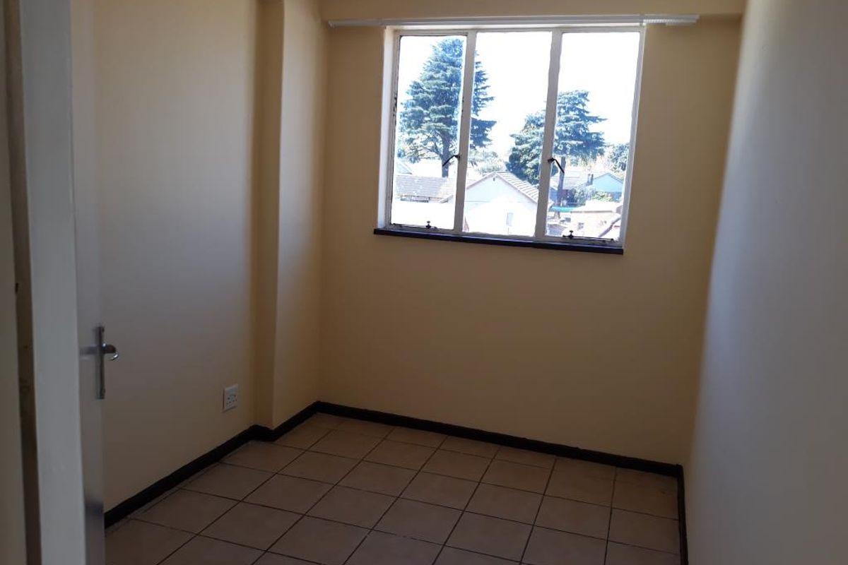 An empty bedroom featuring tiled flooring and a window with natural light, providing a blank canvas for personalization.