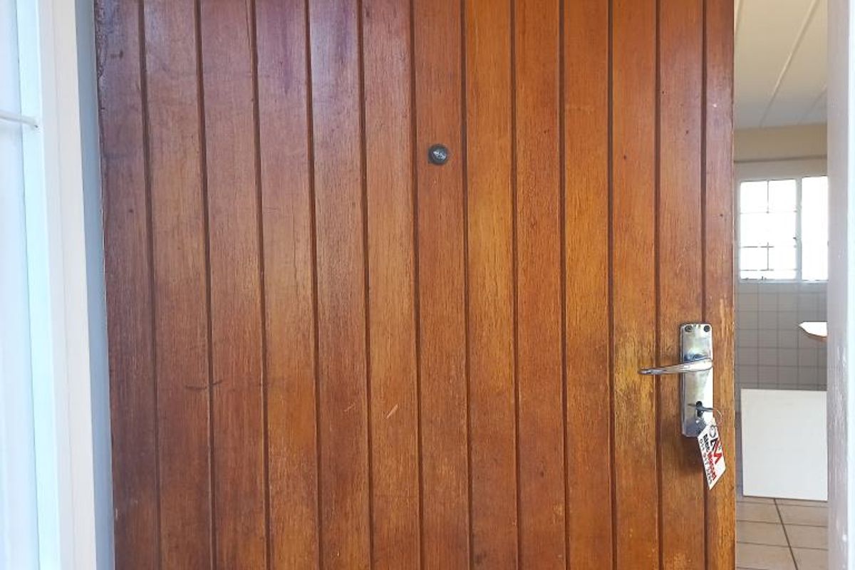 Entrance view of an apartment unit featuring a timber door with unit number 135 and ceramic tiled flooring visible in the background.
