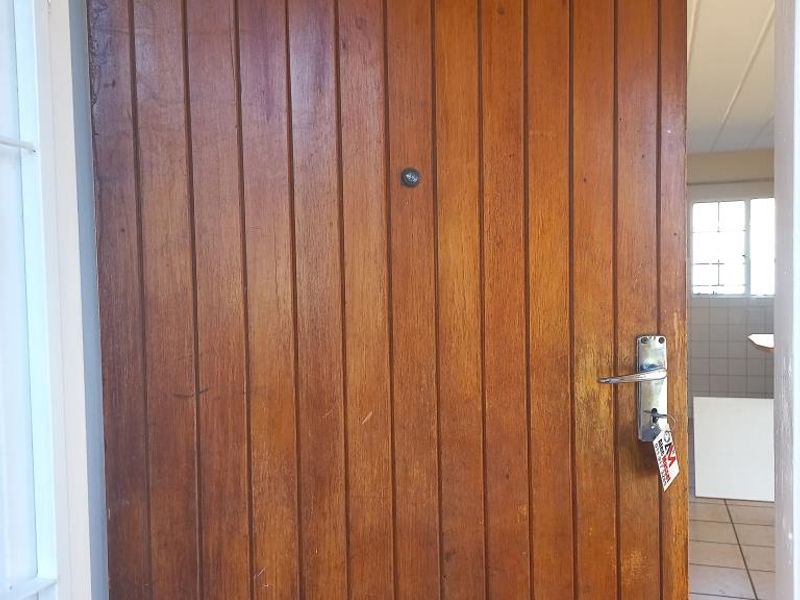 Entrance view of an apartment unit featuring a timber door with unit number 135 and ceramic tiled flooring visible in the background.