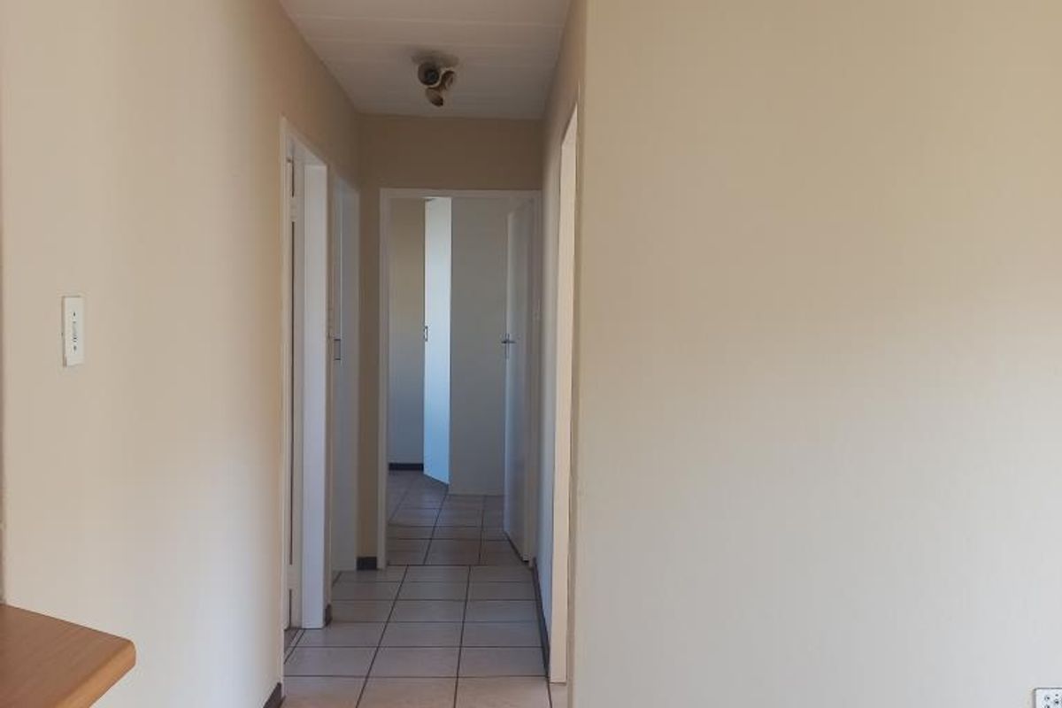 A vacant hallway featuring ceramic floor tiles, neutral wall paint, and multiple internal door access points.