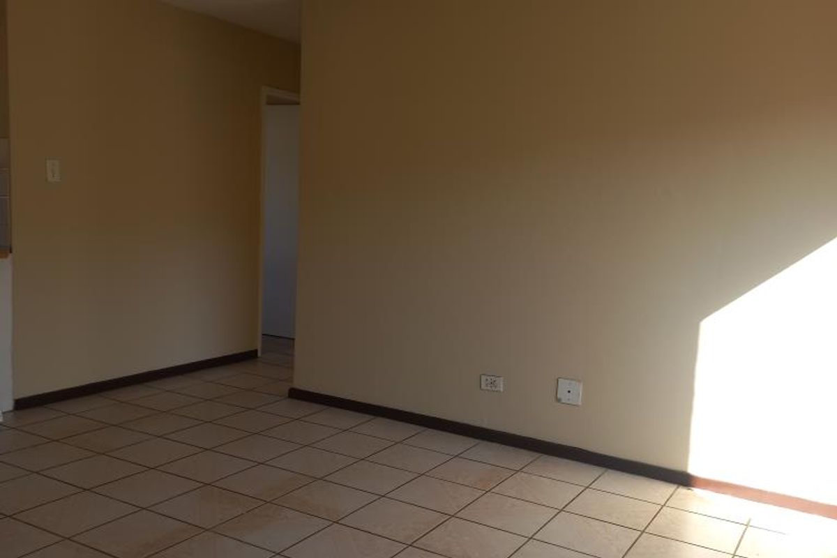 An empty living room featuring tiled flooring and neutral wall tones, offering a blank canvas for potential interior design updates.