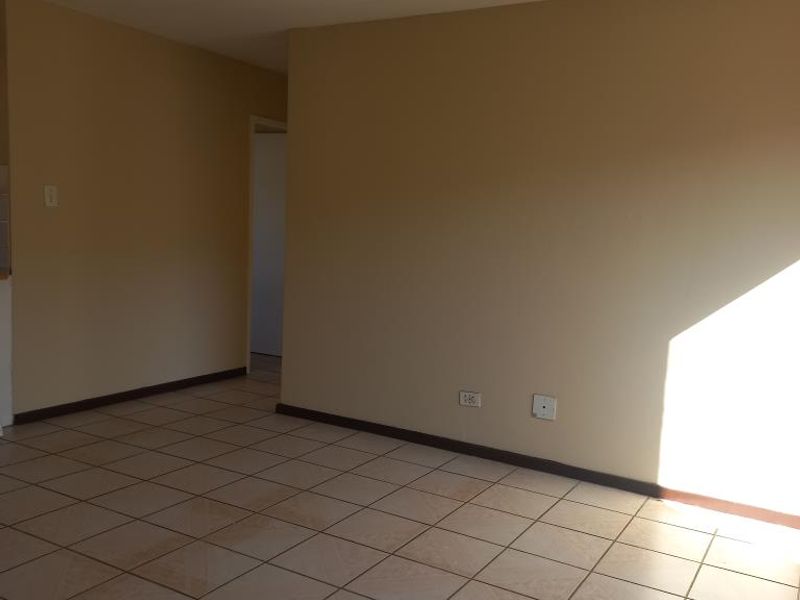 An empty living room featuring tiled flooring and neutral wall tones, offering a blank canvas for potential interior design updates.