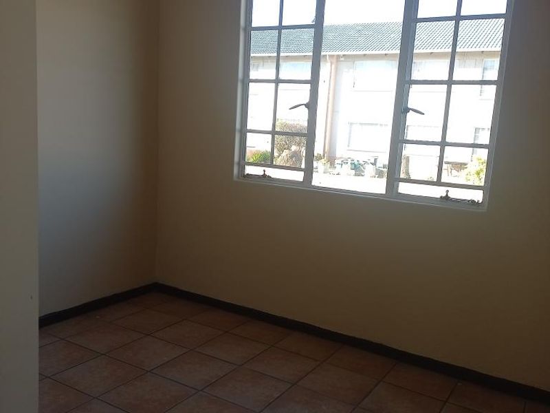 An empty bedroom featuring tiled flooring and a window with muntins, providing a neutral space ready for personalization.