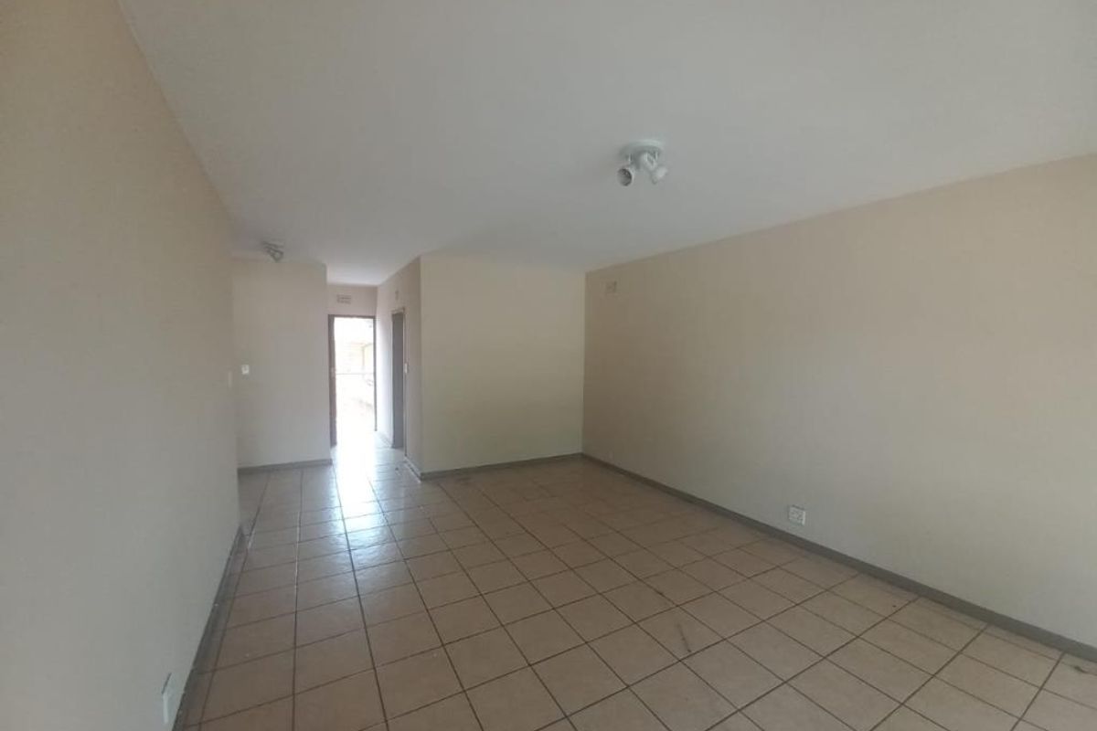 A spacious, empty living area featuring neutral wall tones and tiled flooring, providing a blank canvas for personalization.