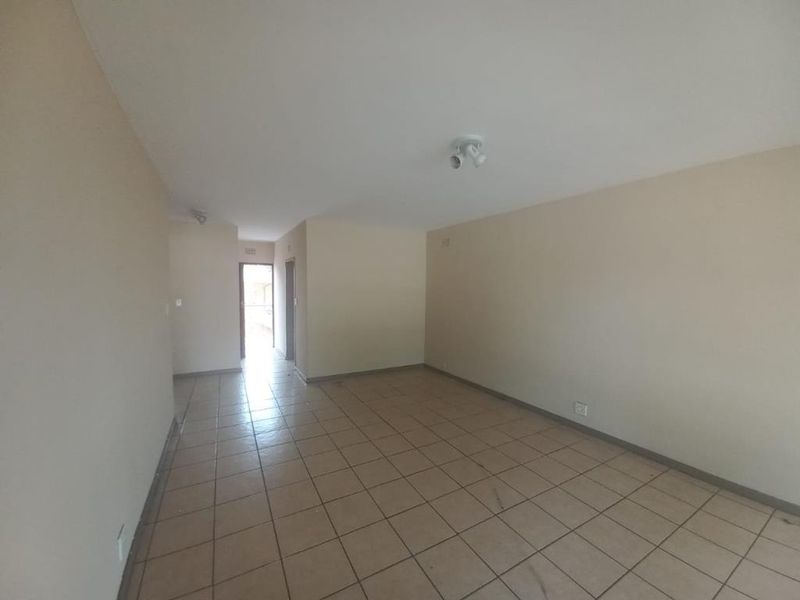 A spacious, empty living area featuring neutral wall tones and tiled flooring, providing a blank canvas for personalization.