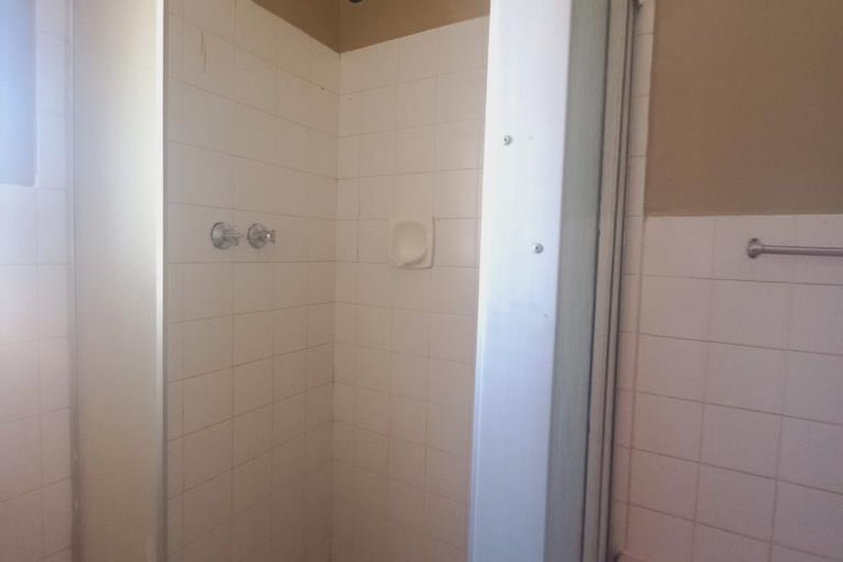 A bathroom featuring a shower enclosure with tiled walls and a mosaic-style tiled floor, alongside a wall-mounted towel rail.