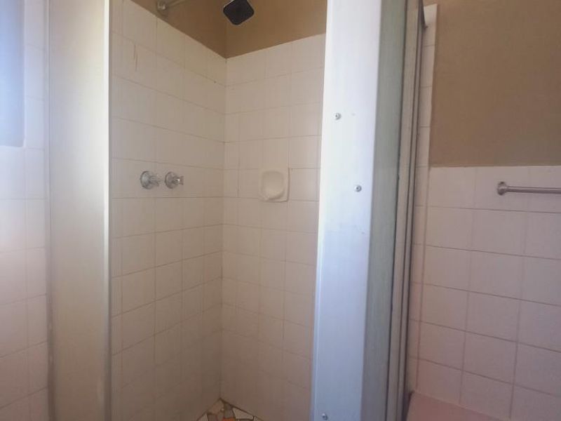 A bathroom featuring a shower enclosure with tiled walls and a mosaic-style tiled floor, alongside a wall-mounted towel rail.
