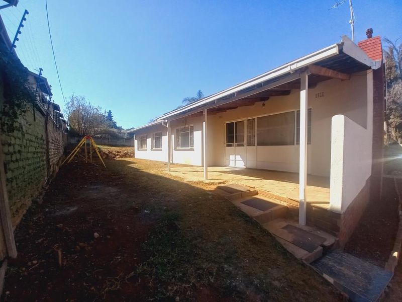 Rear view of the house featuring a covered patio area, brick chimney, and access to the backyard with an existing electric fence.