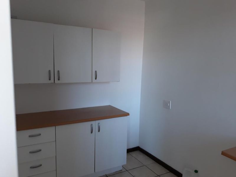 A functional laundry area featuring white built-in cabinetry, a laminate countertop, and tiled flooring, providing ample storage and workspace.