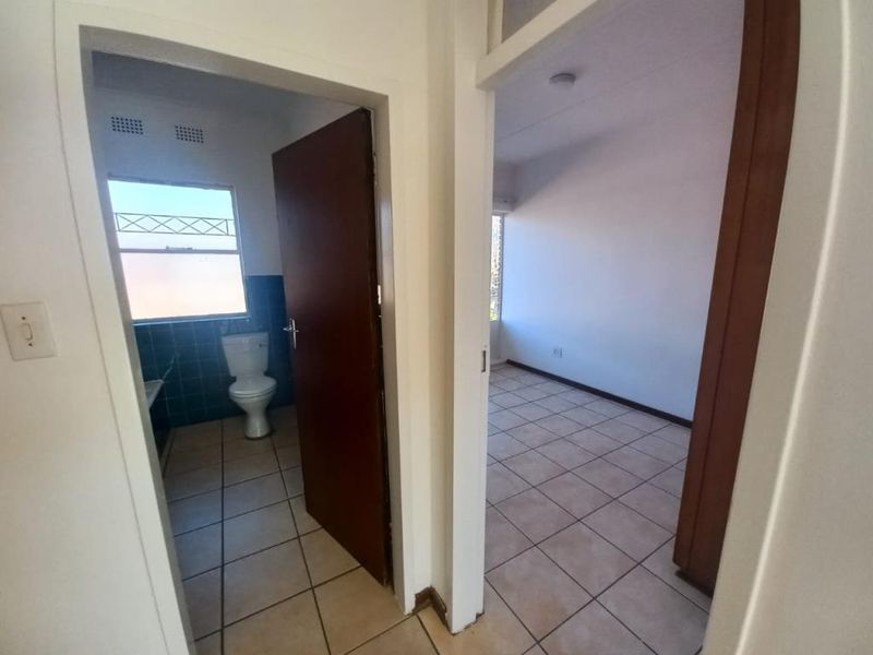 A view from the hallway looking into a bathroom and an adjacent bedroom, featuring tiled flooring throughout and standard internal door frames.