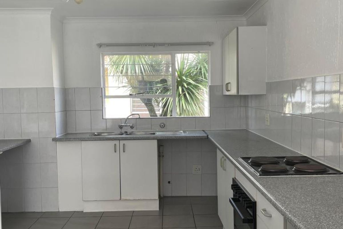 A functional kitchen featuring laminate countertops, built-in electric hob and oven, stainless steel sink, and tiled finishes throughout.