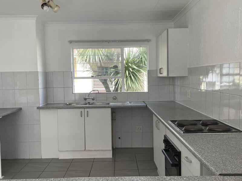 A functional kitchen featuring laminate countertops, built-in electric hob and oven, stainless steel sink, and tiled finishes throughout.