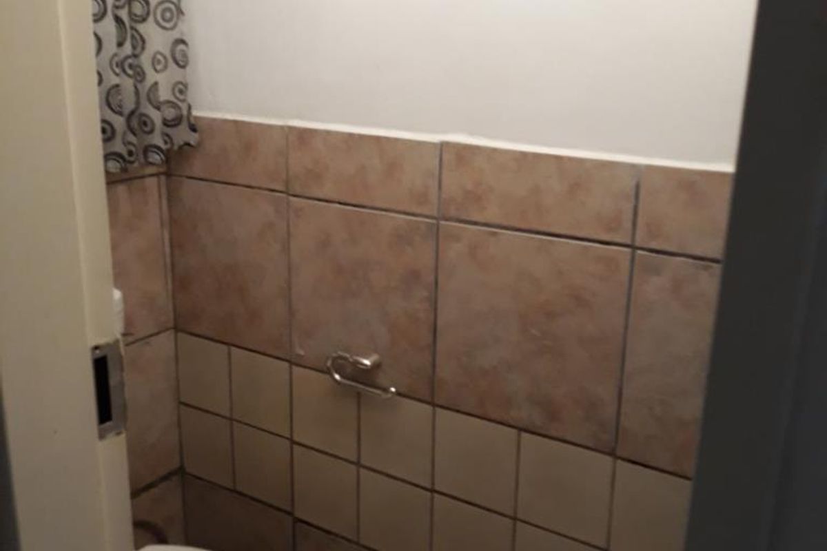 A compact bathroom featuring tiled walls and flooring, equipped with a standard toilet and wall-mounted toilet roll holder.