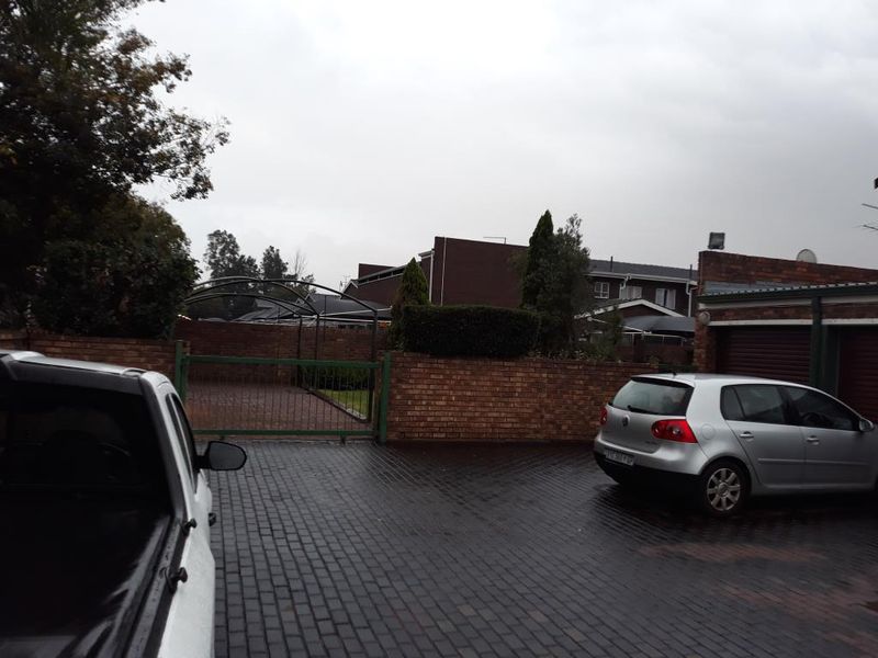 Front exterior view of the property featuring a paved driveway, brick boundary wall, and garage access.