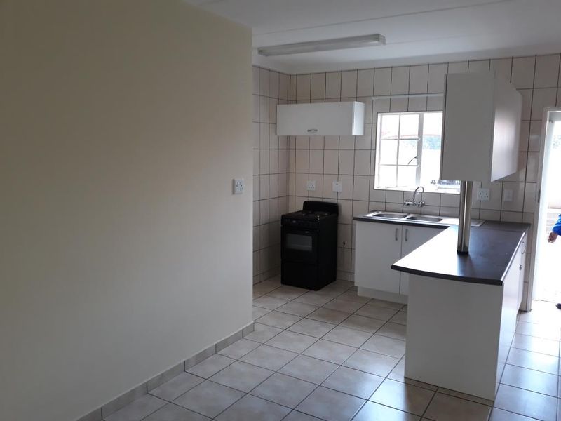 A functional kitchen featuring tiled flooring, a double basin sink, built-in cabinetry, and a breakfast bar, offering a clean and practical layout.