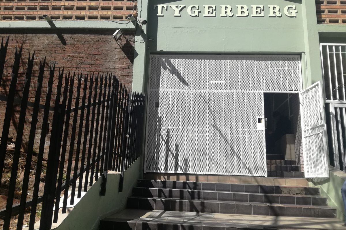 Front entrance of the Tygerberg building featuring a secure metal gate, tiled staircase, and brick facade detailing.
