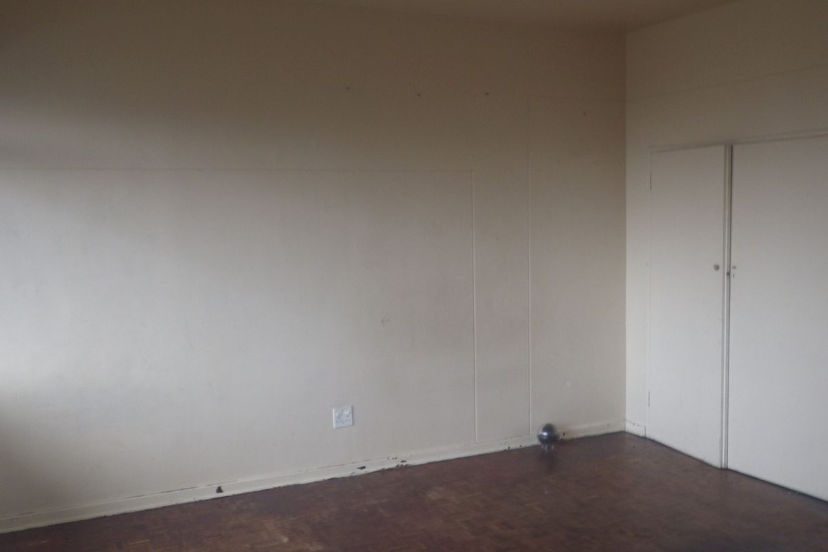 An empty bedroom featuring original parquet flooring and built-in cupboards, requiring cosmetic updates to refresh the space.