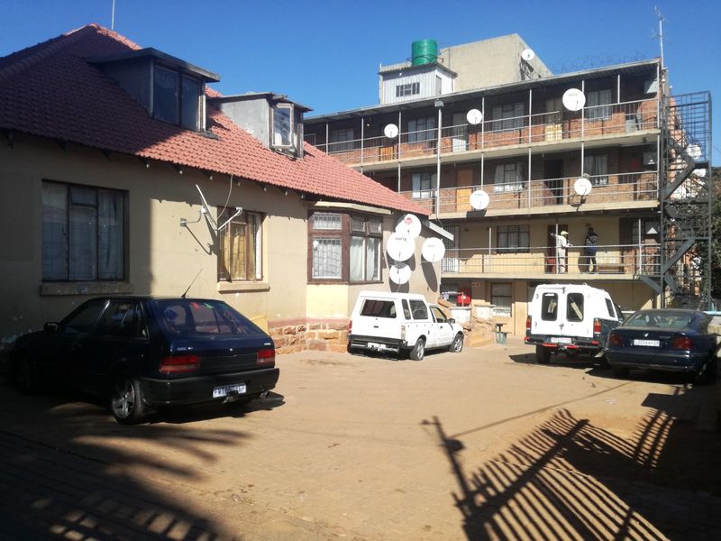 Exterior view of a multi-story apartment complex with a paved driveway and tiled roof building section.