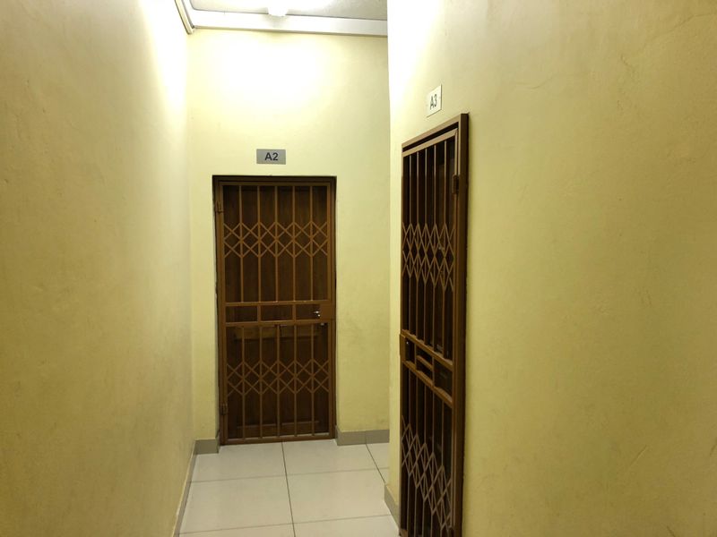 A functional apartment hallway featuring tiled flooring and secure metal security gates for units A2 and A3.