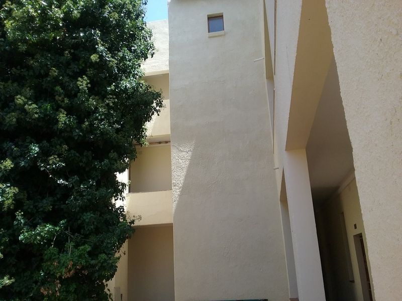 Exterior view of the apartment building facade featuring stucco finish and balcony access.