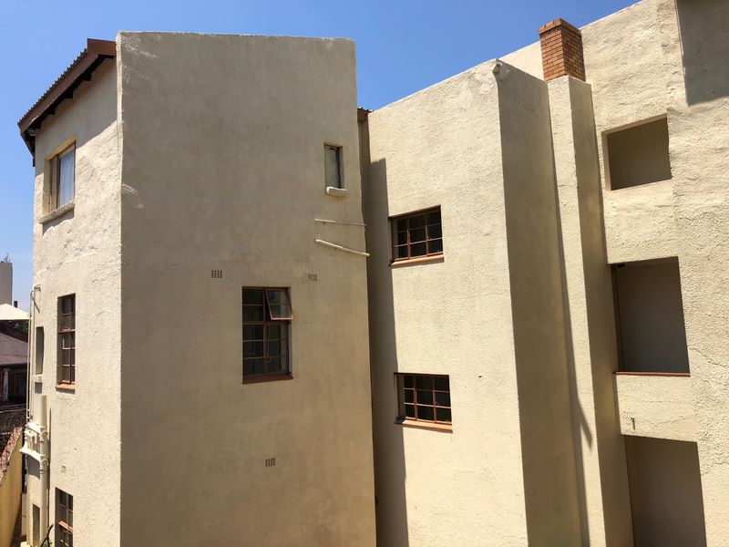 Exterior view of the apartment building facade featuring stucco finish, steel-framed windows, and a brick chimney stack.