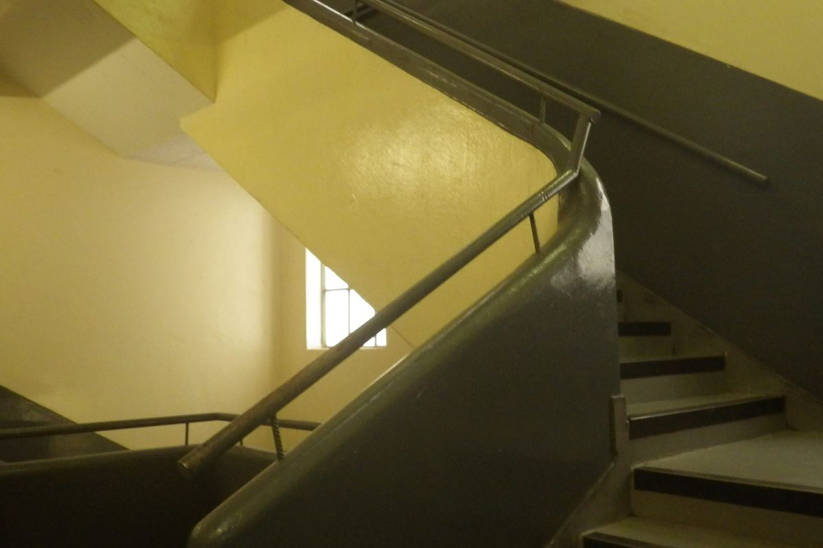 A functional stairwell featuring a metal handrail and painted walls, providing access between levels within the property.