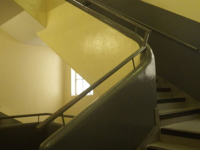 A functional stairwell featuring a metal handrail and painted walls, providing access between levels within the property.