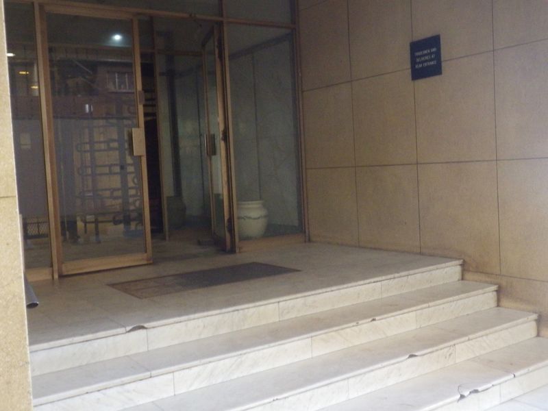 Main building entrance featuring marble steps and glass doors with stone wall cladding.