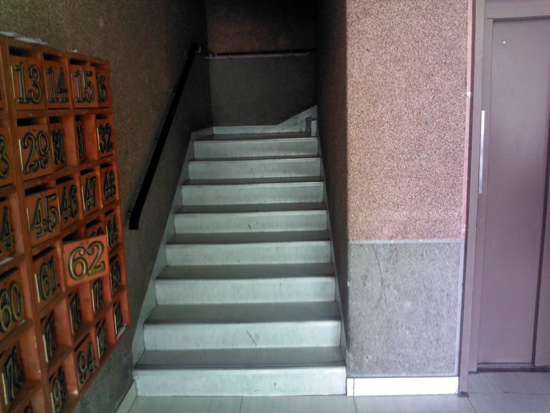 Communal building entrance featuring a staircase with handrail, integrated mailboxes, and access to the elevator.