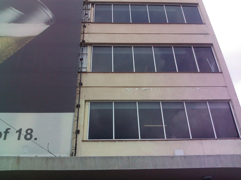 Exterior view of a multi-story flat building facade featuring large windows and a prominent advertising billboard.