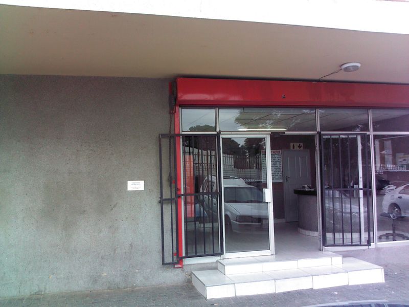 Entrance area of the flat featuring a glass door, security gate, and tiled steps leading into a reception space.