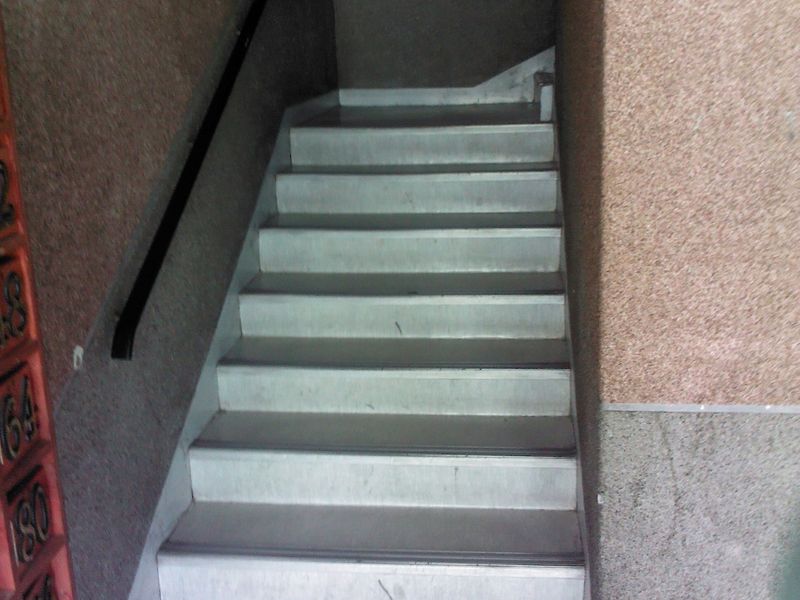 A functional building entrance area featuring a concrete staircase with a handrail and integrated wall-mounted letterboxes.