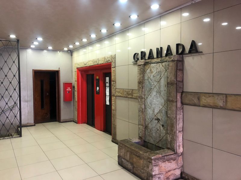 The building entrance lobby features tiled flooring, recessed lighting, a stone water feature, and elevator access.