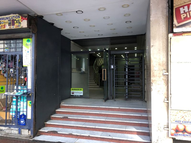 Main building entrance featuring stone steps, glass doors, and a security turnstile, providing access to the lobby area.