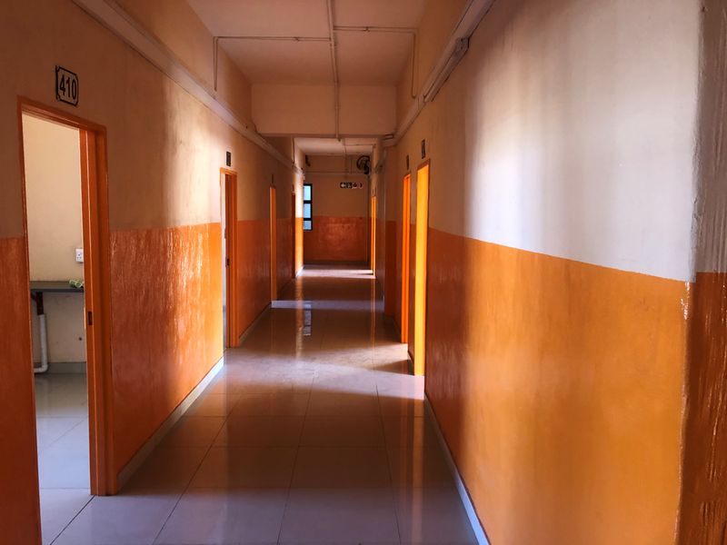A long, vacant apartment hallway featuring tiled flooring and orange-painted lower walls, providing access to multiple rooms.