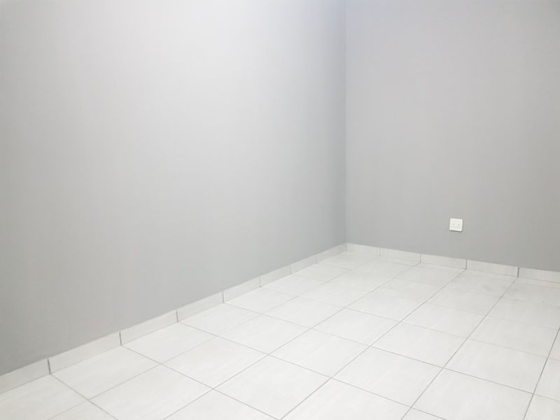 A clean, empty room featuring neutral grey walls and light-colored floor tiles, providing a versatile blank canvas for any interior design style.