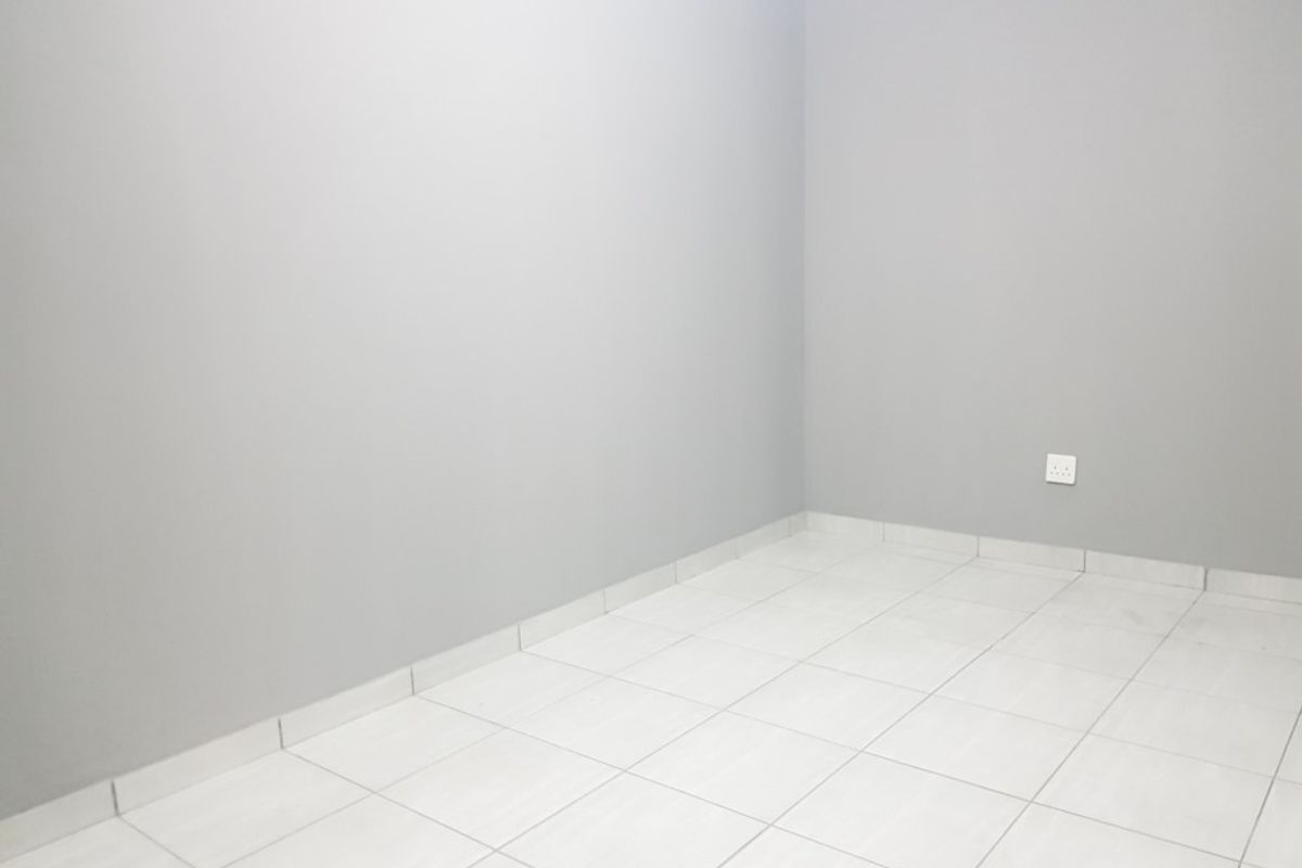A clean, empty room featuring neutral grey walls and light-colored floor tiles, providing a versatile blank canvas for any interior design style.