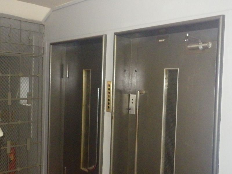 A communal hallway area featuring elevator access doors and a metal security gate enclosure for the staircase.