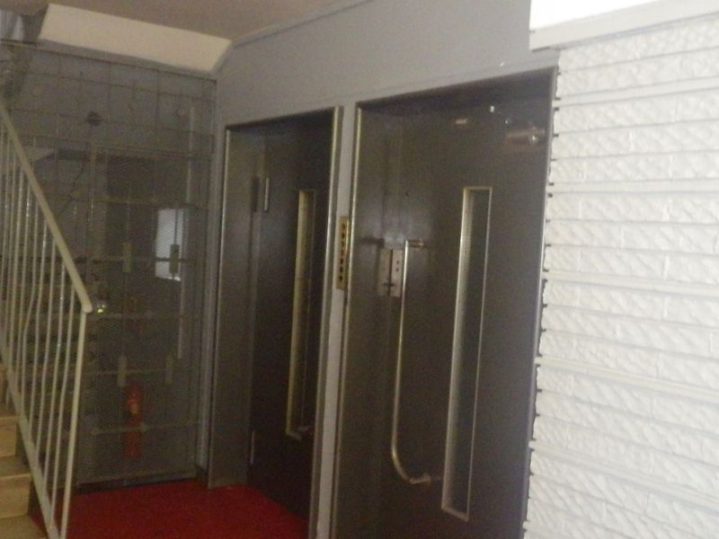 A communal hallway area featuring a staircase with metal balustrade, elevator access, and textured wall finishes.