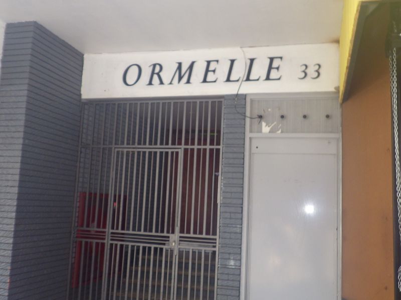 Front entrance of Ormelle 33, featuring a secure metal gate and building signage.