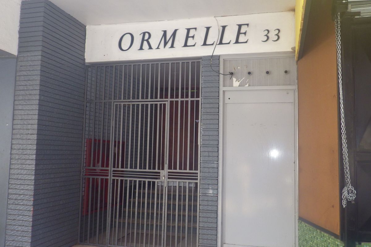 The front entrance of the Ormelle building, featuring a security gate and brick facade.