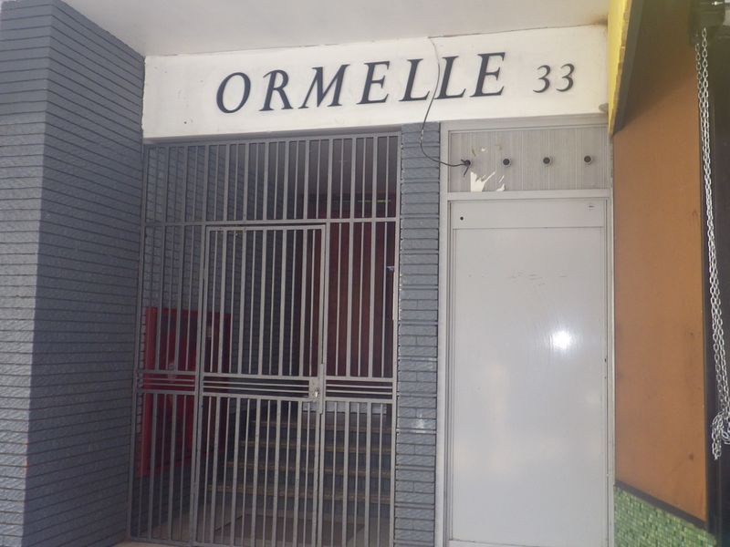 The front entrance of the Ormelle building, featuring a security gate and brick facade.