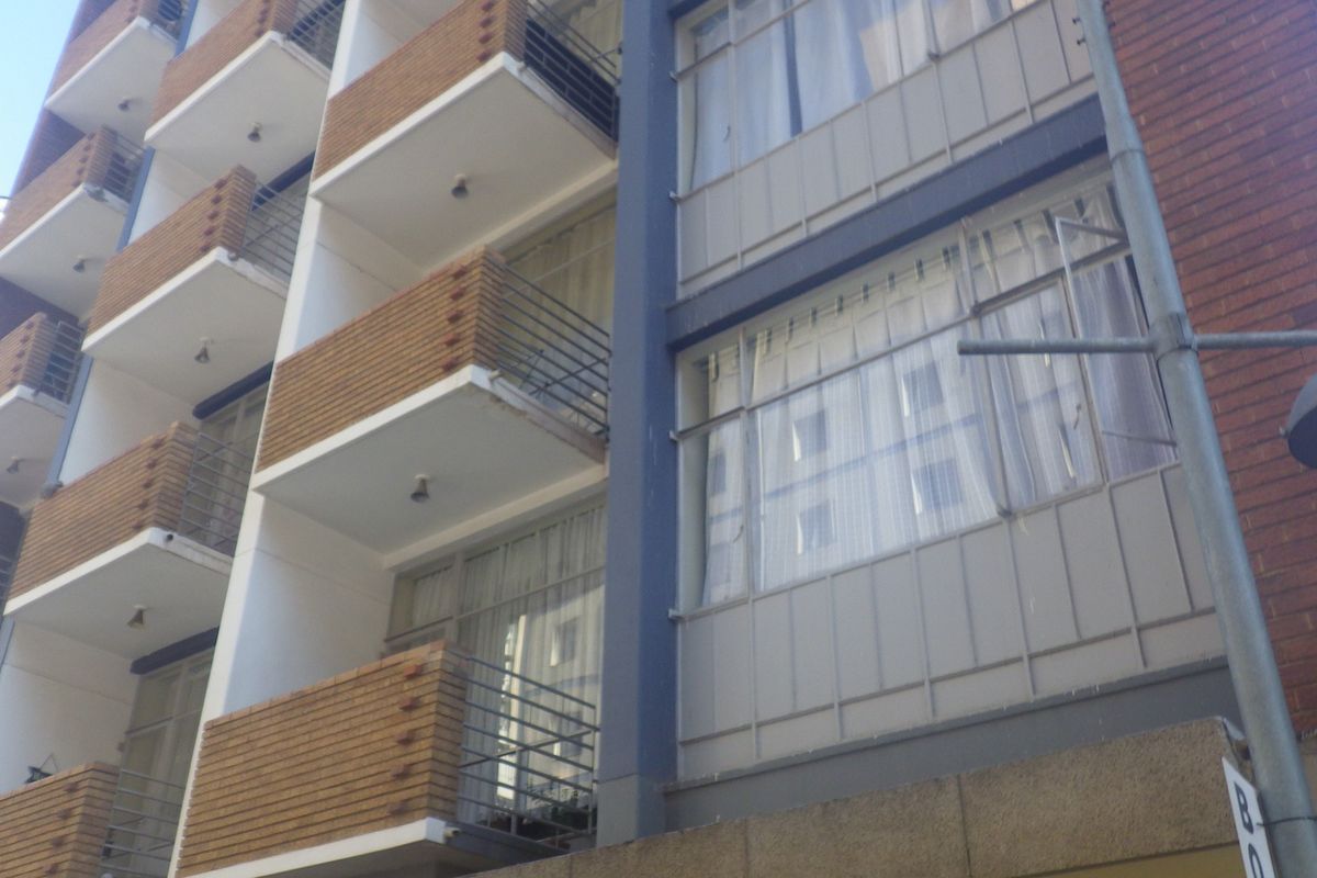 Exterior view of a multi-story apartment building featuring brick facade detailing and private balconies with metal railings.