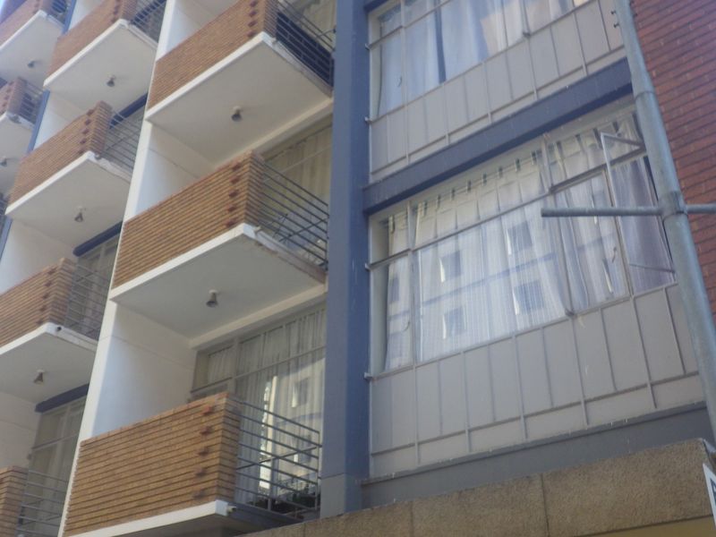 Exterior view of a multi-story apartment building featuring brick facade detailing and private balconies with metal railings.